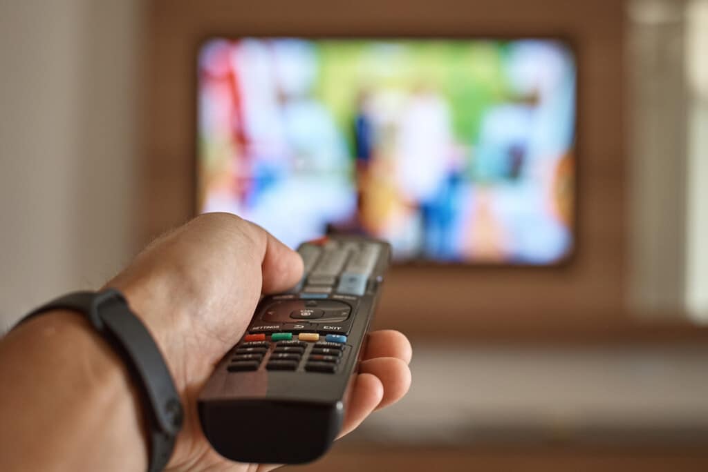 Pessoa com controle remoto de TV na mão simbolizando o uso das redes neurais