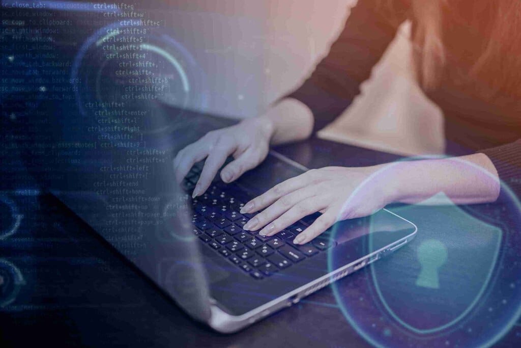 Profissional digitando em laptop com elementos digitais ilustrando o conceito de engenharia de prompt.