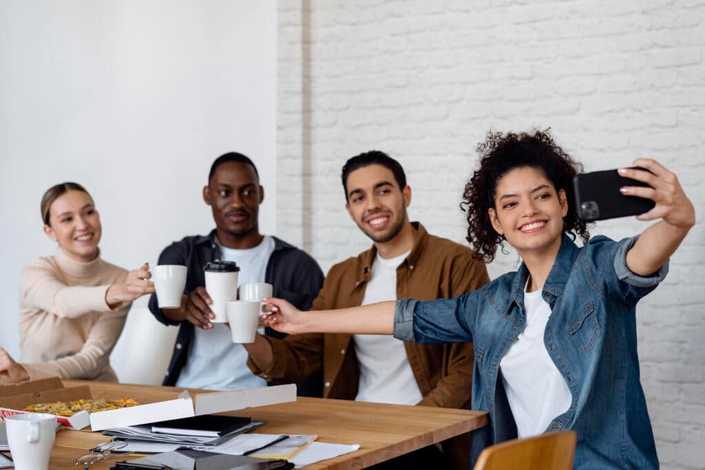 Grupo de colegas tirando selfie no trabalho, representando como a IA para RH pode ajudar no ambiente organizacional.