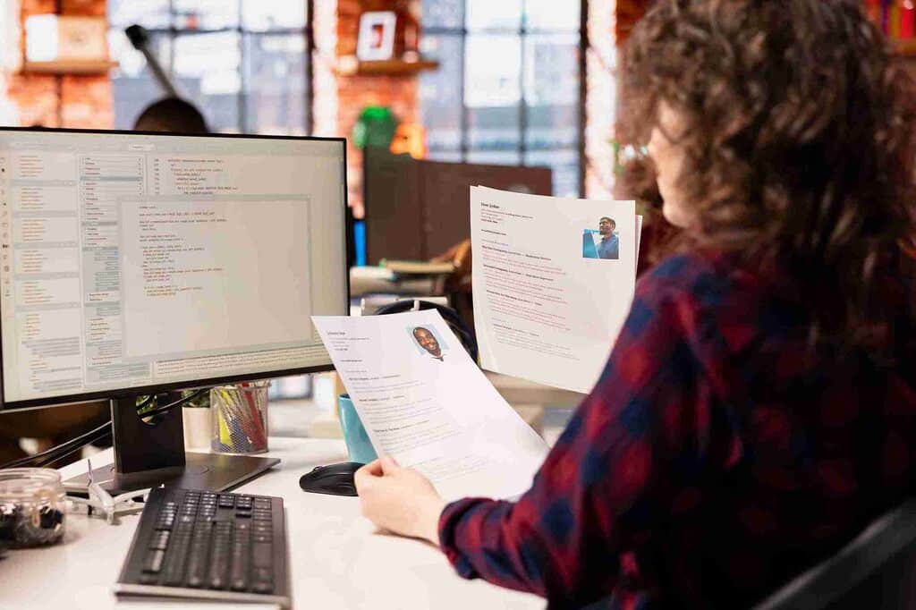 profissional analisando currículo de programação impresso e no computador