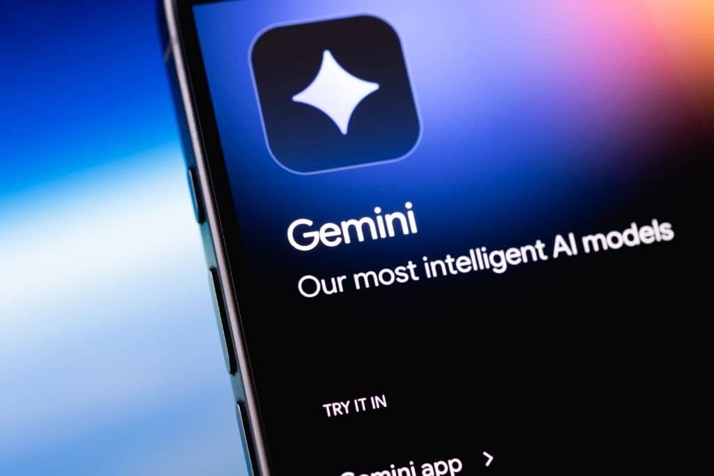 Uma fotografia em close do canto superior de um smartphone exibindo o aplicativo oficial da inteligência de IA do Google. A tela mostra o logotipo brilhante de quatro pontas acima do nome Gemini e a frase afirmando que estes são os modelos de IA mais inteligentes da empresa. O contexto da imagem sugere a disponibilidade multiplataforma da tecnologia que alimenta o Gemini CLI e como ela se integra ao ecossistema de produtividade do usuário em diferentes dispositivos.