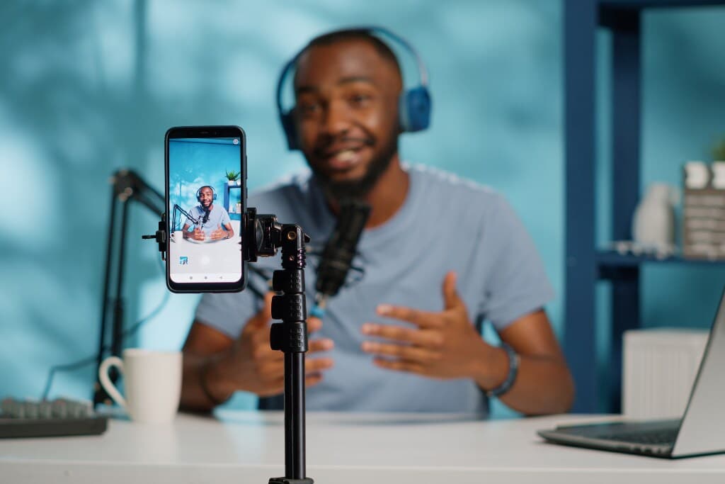 Criador de conteúdo gravando vídeo explicativo sobre bubble usando smartphone, microfone profissional e setup moderno de produção digital.