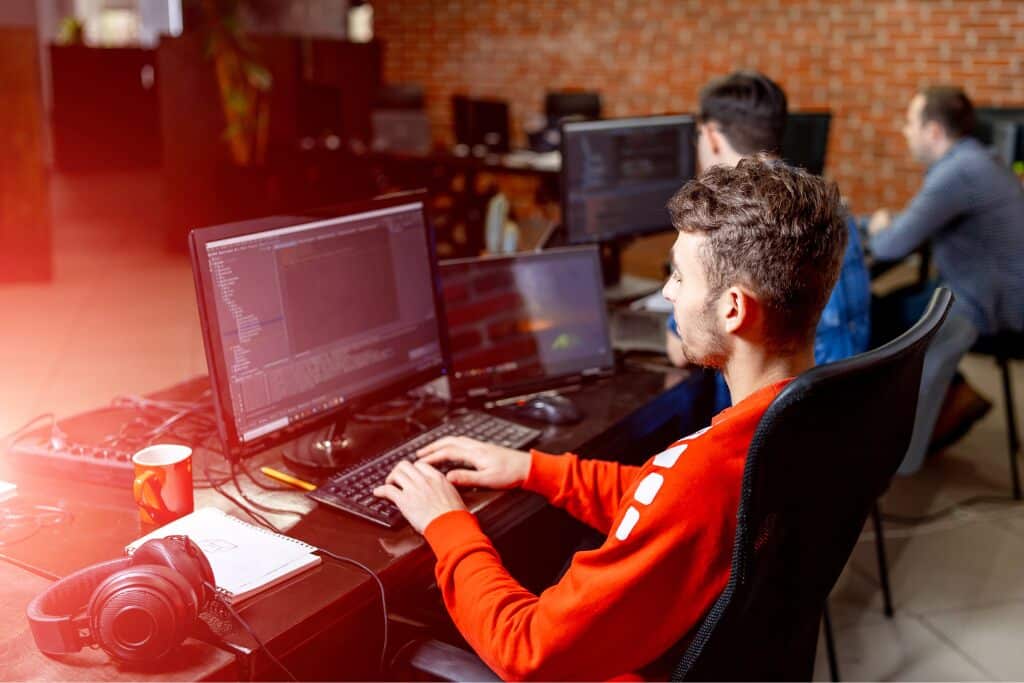 Programador desenvolvendo aplicação em computadores modernos durante curso bubble com foco em tecnologia, automação e desenvolvimento digital.