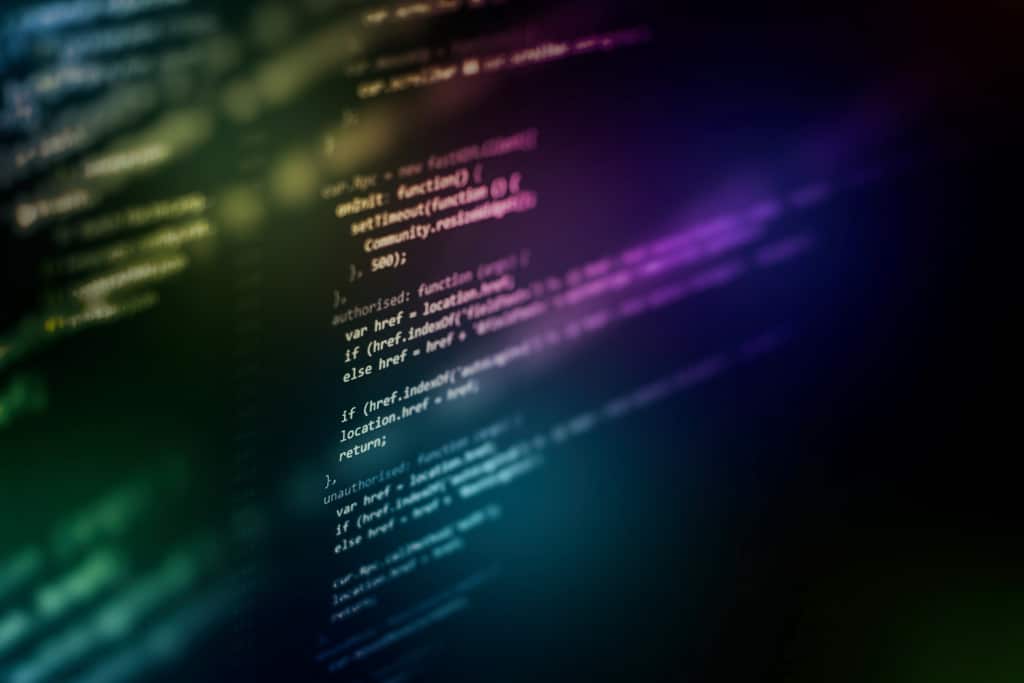 Código colorido desfocado em tela escura representando lógica e estruturas while em python.